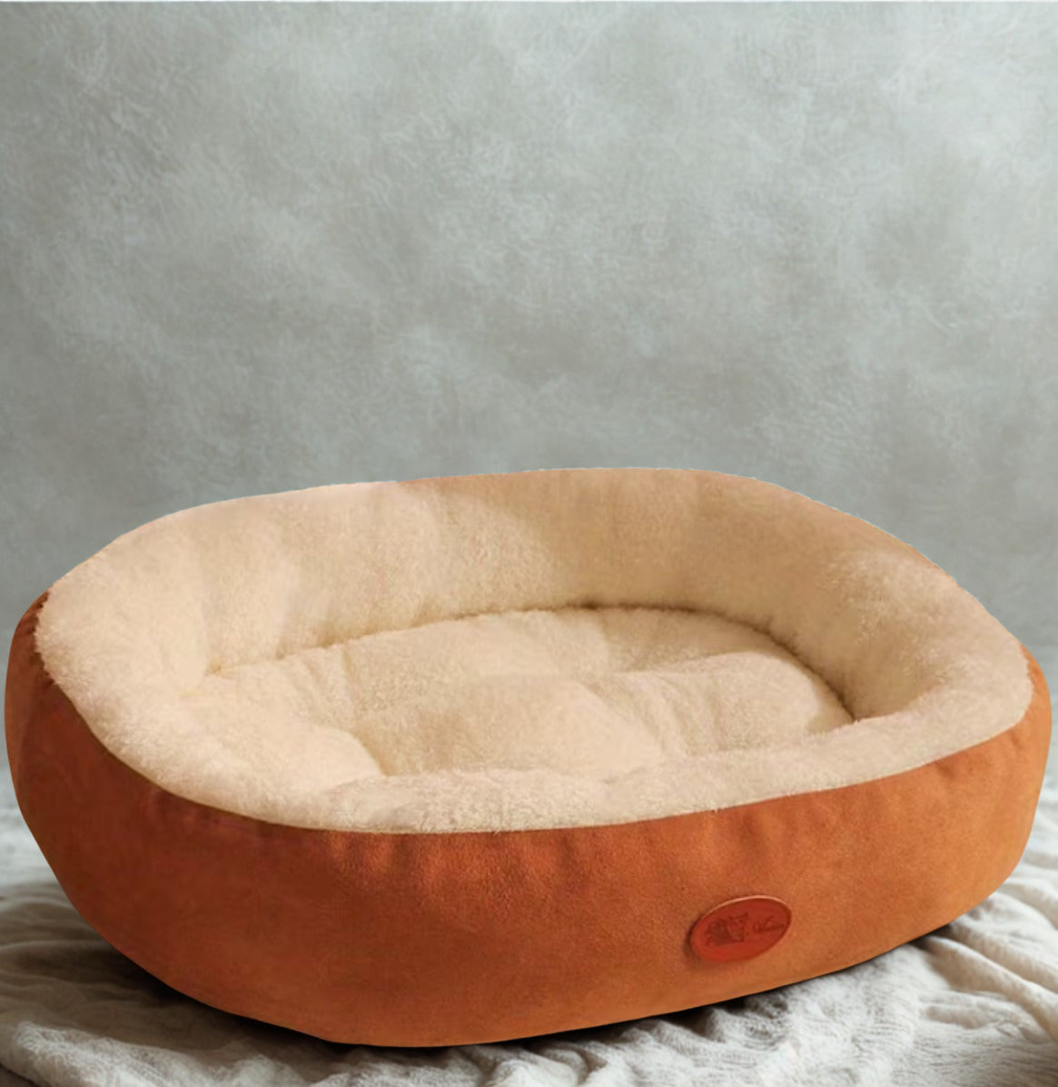 Round pet bed with brown exterior and beige interior on a textured surface